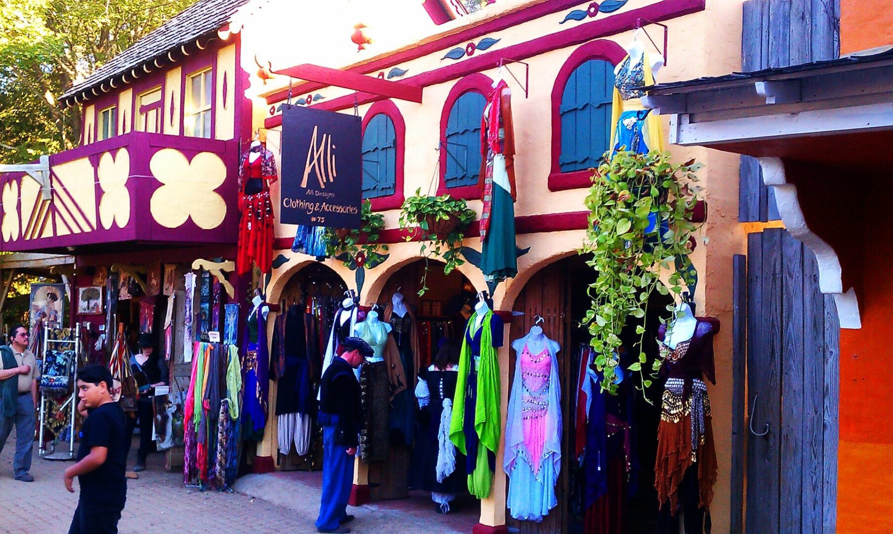 A store front with many different colored clothes hanging.