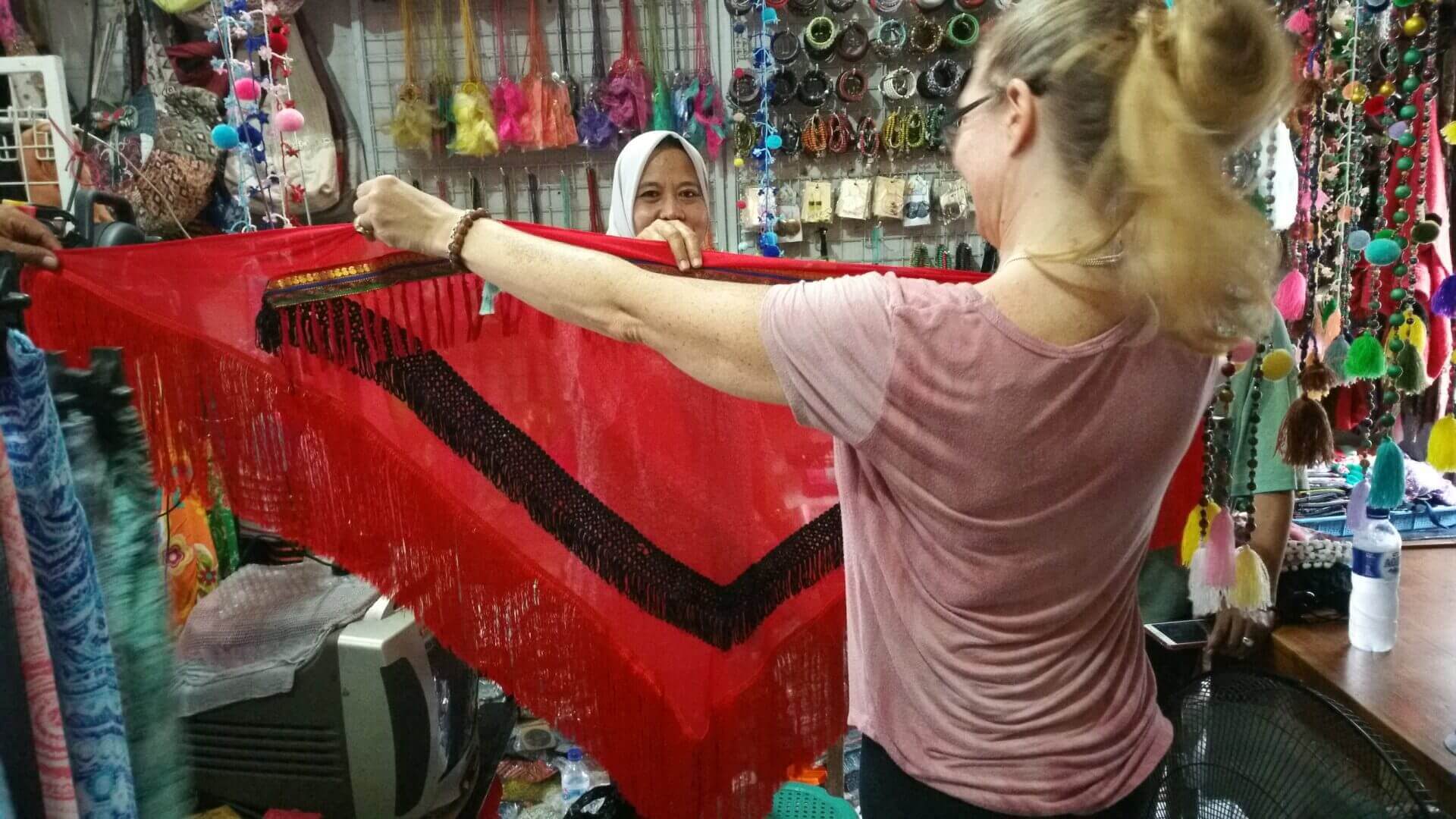 A woman is weaving in a shop with other people.