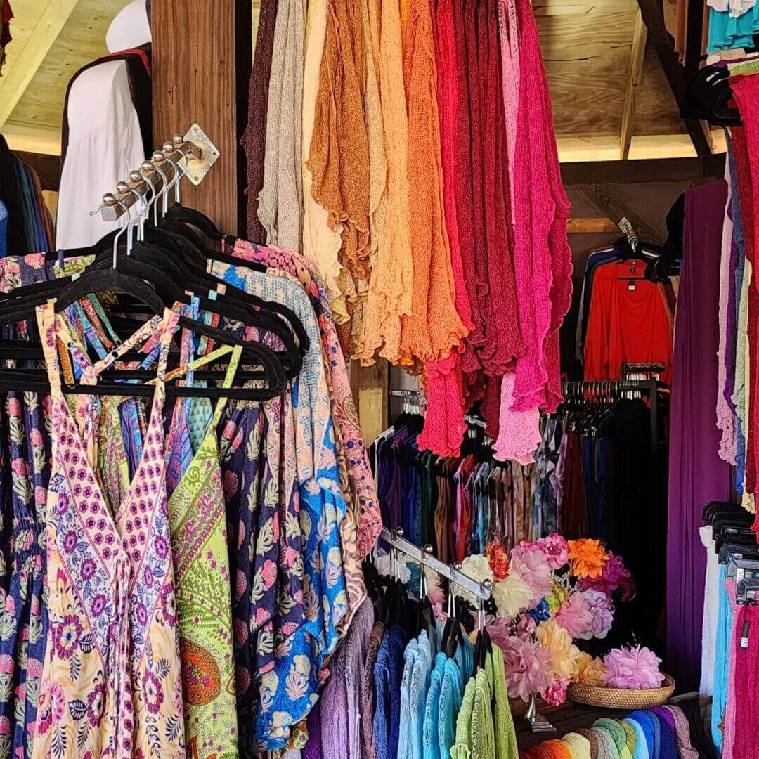 A bunch of colorful clothes hanging in a room