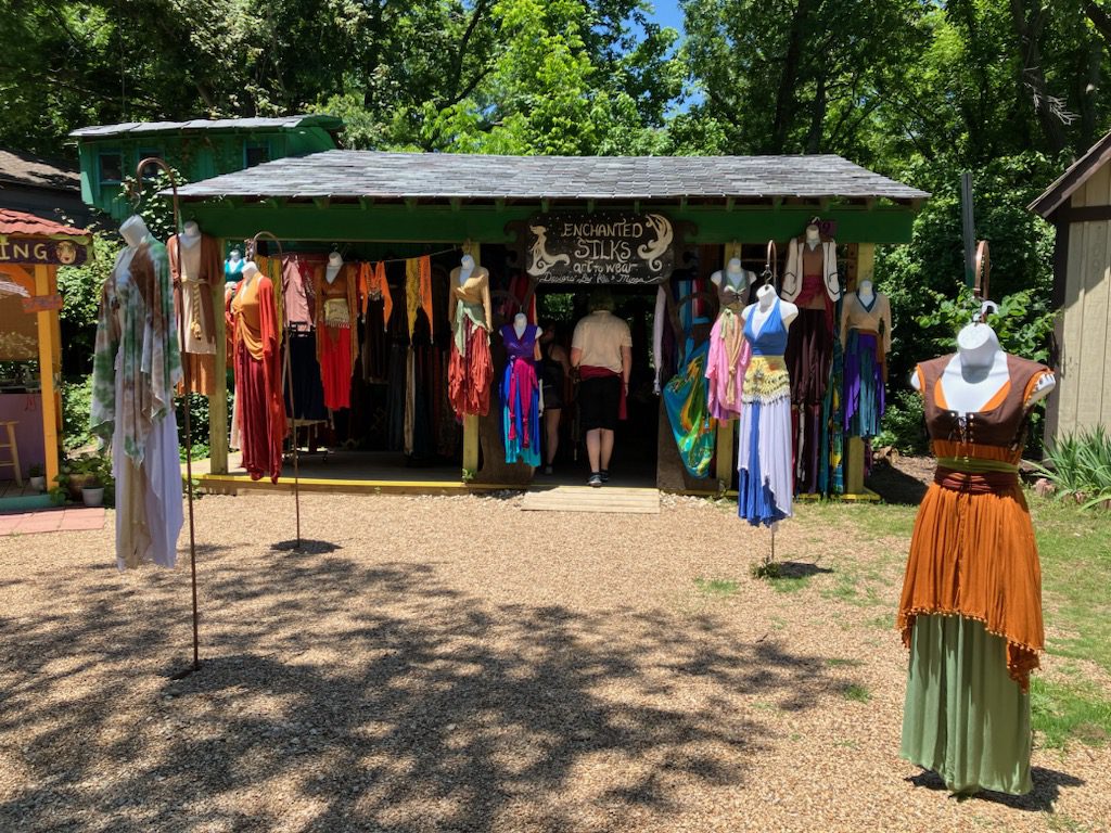 A woman standing in front of a store with many dresses on display.